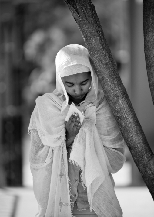Black and white portrait of an orthodox woman praying with a bible, Harar, Ethiopia