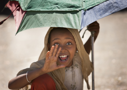 Portrait Of A Young Ethiopian Girl Under Her Umbrella Waving At Camera, Harar, Ethiopia