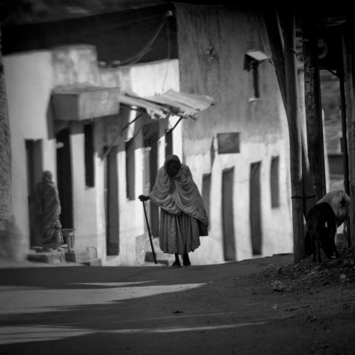 Black And White Picture Of An Old Woman Walking In A Narrow Street In The Old Town Of Harar, Ethiopia