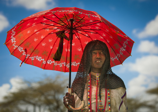 Karrayyu Tribe Woman With Black Headscarf And Colourful Necklaces Under A Red Umbrella, Metahara, Ethiopia