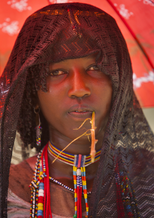Karrayyu Tribe Woman With Black Headscarf And Colourful Necklaces Under A Red Umbrella, Metahara, Ethiopia