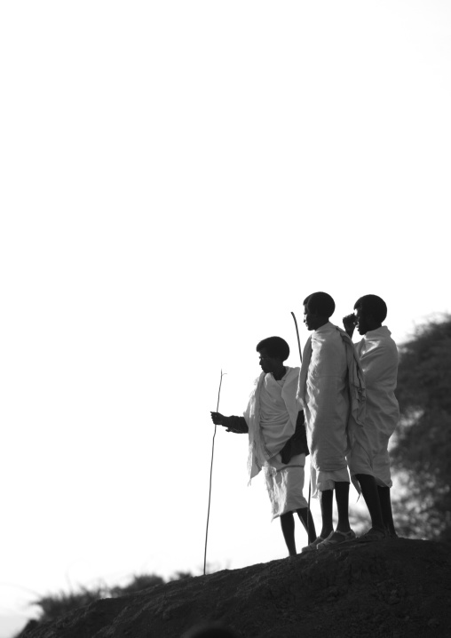Three Karrayyu Tribe Men With Gunfura Hairstyle And Traditional Clothes Standing On Top Of A Hill During Gadaaa Ceremony, Metahara, Ethiopia