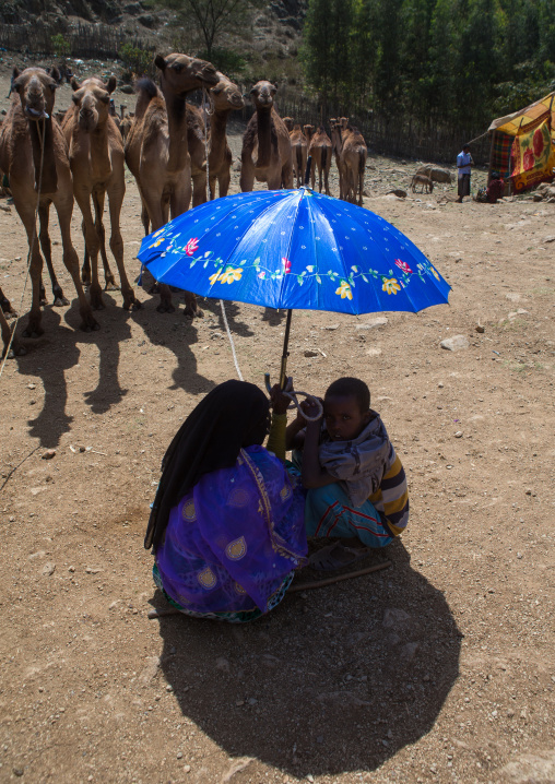 People protecting from the sun under an umbrella in the camel market, Oromo, Sambate, Ethiopia