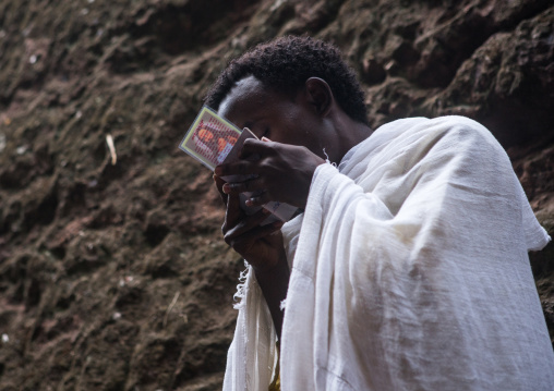 Ethiopian orthodox man kissing his bible, Amhara region, Lalibela, Ethiopia