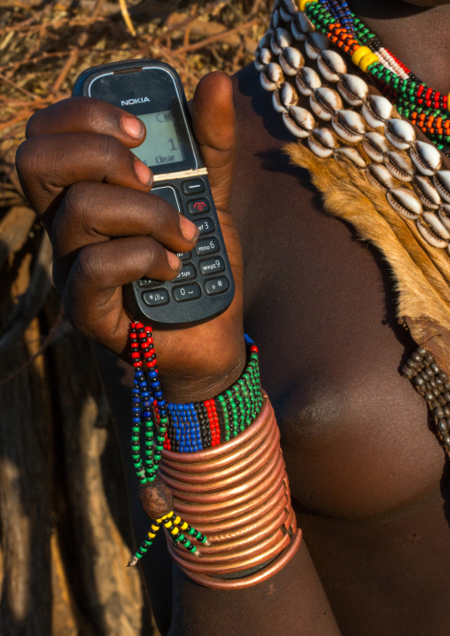 Hamer tribe girl with brass bracelets holding a nokia mobile phone, Omo valley, Turmi, Ethiopia