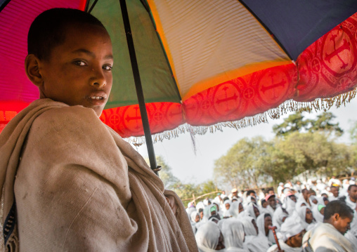 Boy holding an umbrella during kidane mehret orthodox celebration, Amhara region, Lalibela, Ethiopia