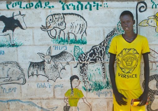 Toposa tribe boy in front of a school mural, Omo valley, Kangate, Ethiopia