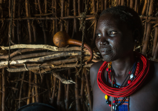 Toposa tribe woman with scarified face and red necklaces, Omo valley, Kangate, Ethiopia