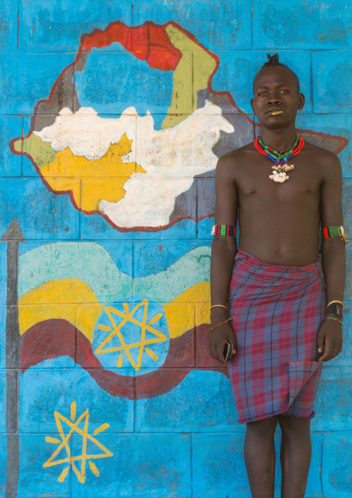 Hamer tribe teenager in a school in front of a painted wall with the ethiopian map, Omo valley, Turmi, Ethiopia