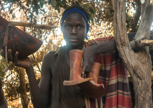 Circumcised boy from the dassanech tribe with their traditional wooden seat, Omo valley, Omorate, Ethiopia