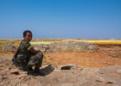 Ethiopian female soldier in front of colorful volcanic landscape in the danakil depression, Afar region, Dallol, Ethiopia
