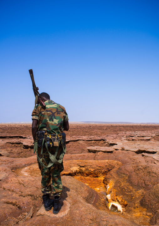 An ethiopian soldier in front of an acid lake in the danakil depression, Afar region, Dallol, Ethiopia