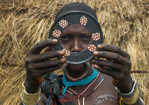 A mursi tribeswoman holding a traditional lip-plate, Omo valley, Mago park, Ethiopia