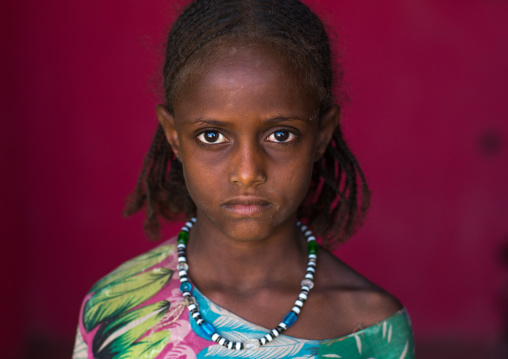 Portrait of an afar tribe girl on a red background, Afar region, Semera, Ethiopia