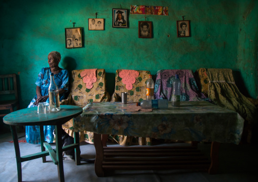 Old woman inside her house decorated with old pictures of her relatives, Omo valley, Jinka, Ethiopia