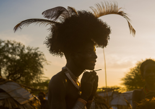 Dassanech man dressing with a ostrich feathers headwear for dimi ceremony to celebrate circumcision of the teenagers, Omo valley, Omorate, Ethiopia