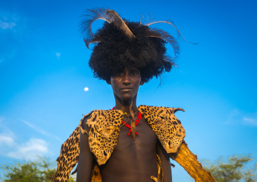 Dassanech man with leopard skin and ostrich feathers headwear during dimi ceremony to celebrate circumcision of teenagers, Omo valley, Omorate, Ethiopia