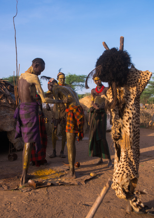 A dassanech man puts some mud on his friend body to join the dimi ceremony, Omo valley, Omorate, Ethiopia