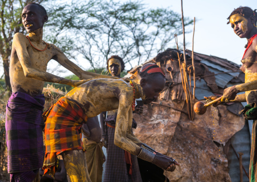 A dassanech man puts some mud on his friend body to join the dimi ceremony, Omo valley, Omorate, Ethiopia