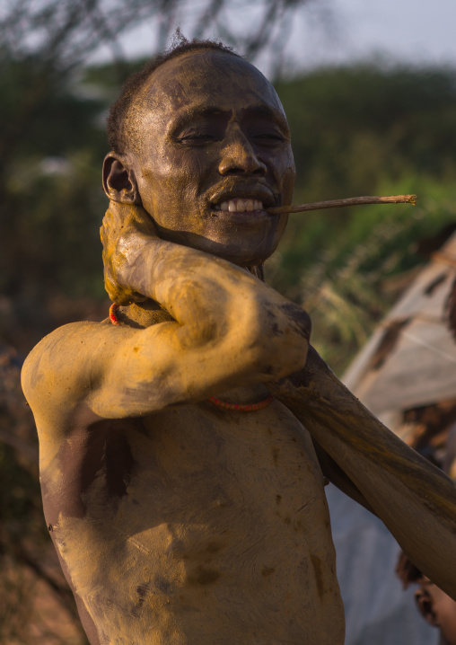 Dassanech man putting mud on his body during dimi ceremony to celebrate circumcision of the teenagers, Omo valley, Omorate, Ethiopia