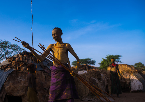 Dassanech man preparing the long sticks for dimi ceremony to celebrate circumcision of teenagers, Omo valley, Omorate, Ethiopia