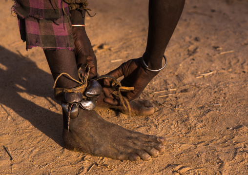 Dassanech man putting bells on the legs dimi ceremony to celebrate circumcision of the teenagers, Omo valley, Omorate, Ethiopia