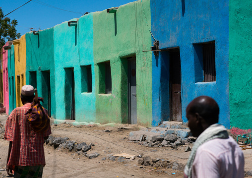 Men passing in front multi colored houses, Afar region, Assayta, Ethiopia