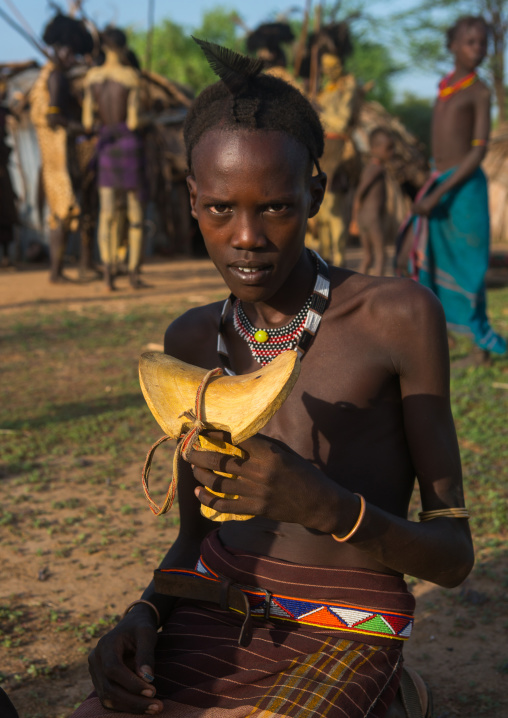 Circumcised boy from the dassanech tribe showing his adult new wooden seat, Omo valley, Omorate, Ethiopia