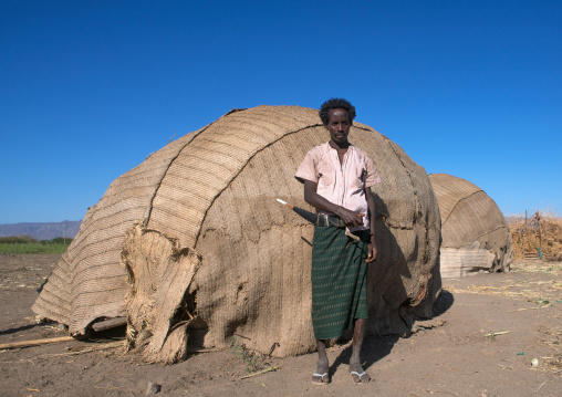 Afar tribe man with his guile knife in front of his hut, Afar region, Afambo, Ethiopia