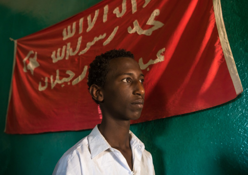 Sufi man worshipper in front of islamic red flag, Harari region, Harar, Ethiopia