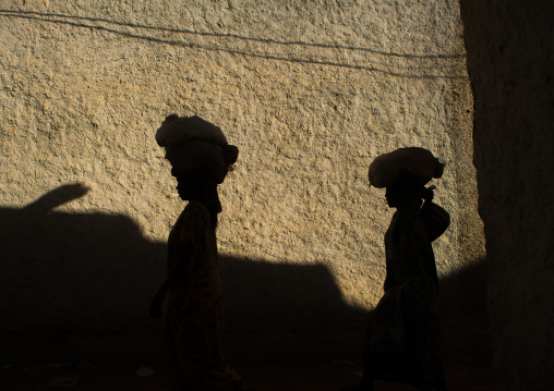 Shadow of two women carrying stuff on their heads on a wall of the old city, Harari region, Harar, Ethiopia