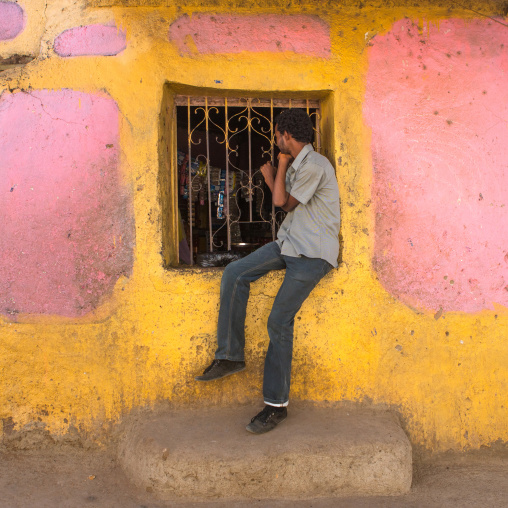 Man sit on the window of a little shop in the old town, Harari region, Harar, Ethiopia