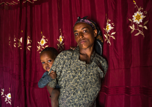 Ethiopia, Kembata, Alaba Kuito, mother and baby inside their house in front of a red curtain