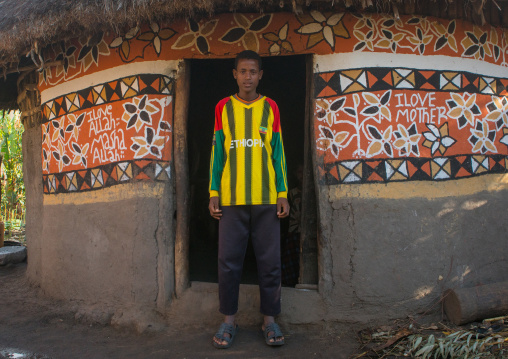 Ethiopia, Kembata, Alaba Kuito, young man standing in front of his traditional painted house with a shirt of the football national teram