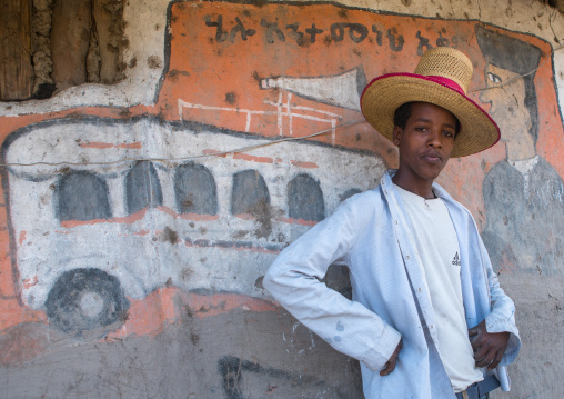 Ethiopia, Kembata, Alaba Kuito, ethiopian young man with a hat standing in front of his traditional painted house