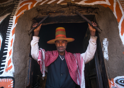 Ethiopia, Kembata, Alaba Kuito, ethiopian muslim man with a hat standing in front of his traditional painted house
