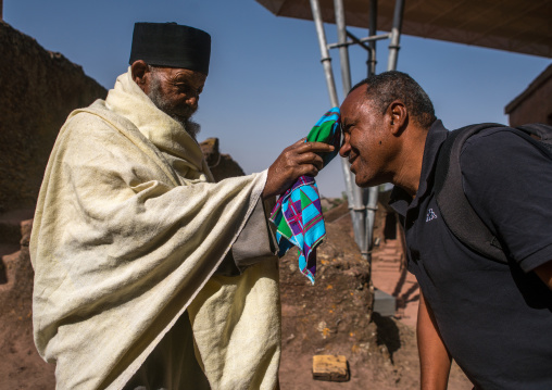 Ethiopian priest blessing a visitor during kidane mehret orthodox celebration, Amhara region, Lalibela, Ethiopia