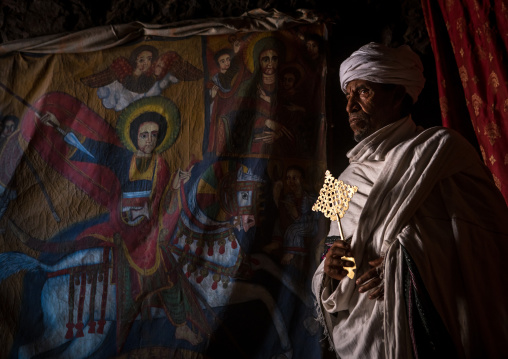 Portrait of an ethiopian orthodox priest holding a cross inside a rock church, Amhara region, Lalibela, Ethiopia