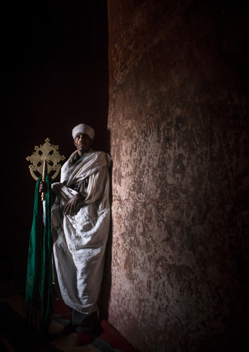 Ethiopian orthodox priest holding a cross inside a rock church, Amhara region, Lalibela, Ethiopia