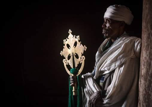 Portrait of an ethiopian orthodox priest holding a cross inside a rock church, Amhara region, Lalibela, Ethiopia