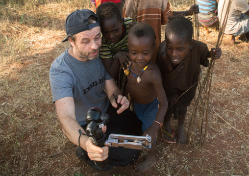 Tourist showing the screen of his camera to hamer tribe people, Omo valley, Turmi, Ethiopia