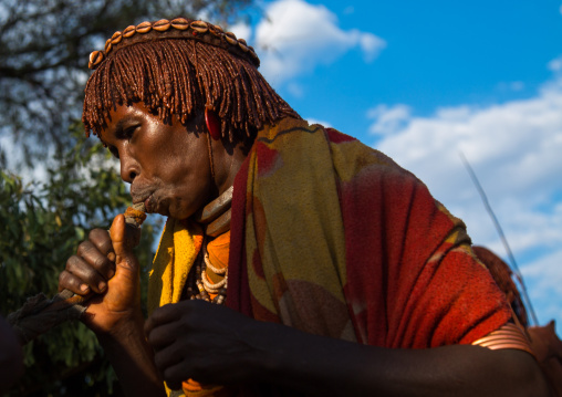 Hamer tribe women blowing in a horn during a bull jumping ceremony, Omo valley, Turmi, Ethiopia