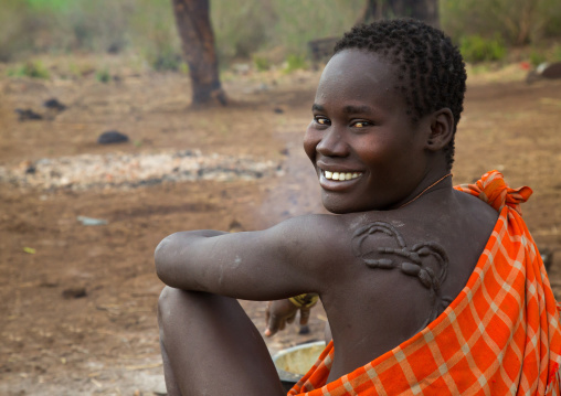 Smiling bodi tribe woman with impressive scarifications on the back, Omo valley, Hana mursi, Ethiopia