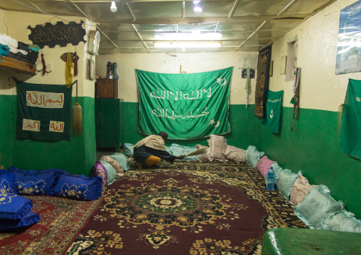 Man cleaning a room decorated with islam flags before a sufi celebration, Harari Region, Harar, Ethiopia