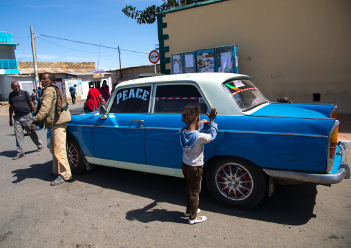 Child oeping the door of an old peugeot 404 taxi, Harari Region, Harar, Ethiopia