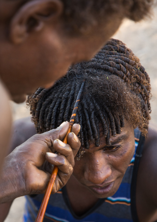 Afar man having a traditional hairstyle with a stick to make curly hair, Afar region, Afambo, Ethiopia
