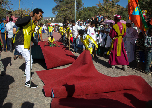 Ethiopian men unfolding red carpets for the priests who carry tabots during Timkat epiphany festival, Amhara region, Lalibela, Ethiopia