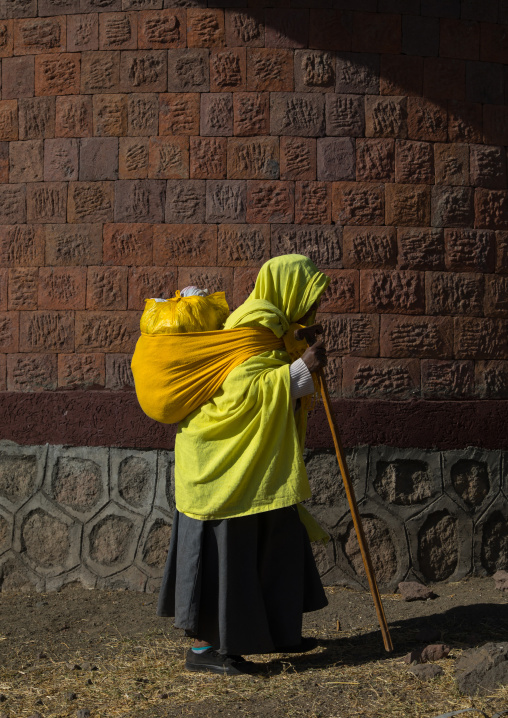 Ethiopian monk woman walking with a heavy bag on her back, Amhara region, Lalibela, Ethiopia
