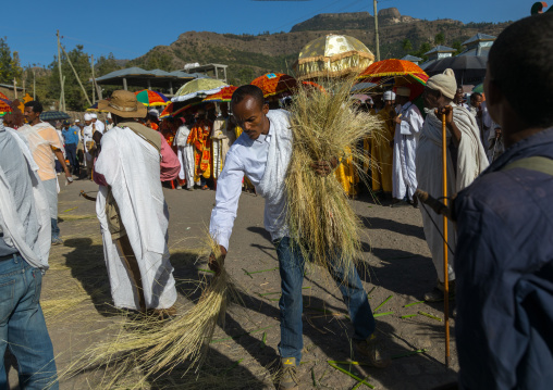 Ethiopian man putting straw on the path of the priests who will carry tabots during Timkat epiphany festival, Amhara region, Lalibela, Ethiopia