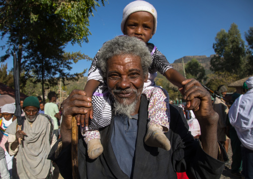 Ethiopian father carrying his son on his back during Timkat epiphany festival, Amhara region, Lalibela, Ethiopia